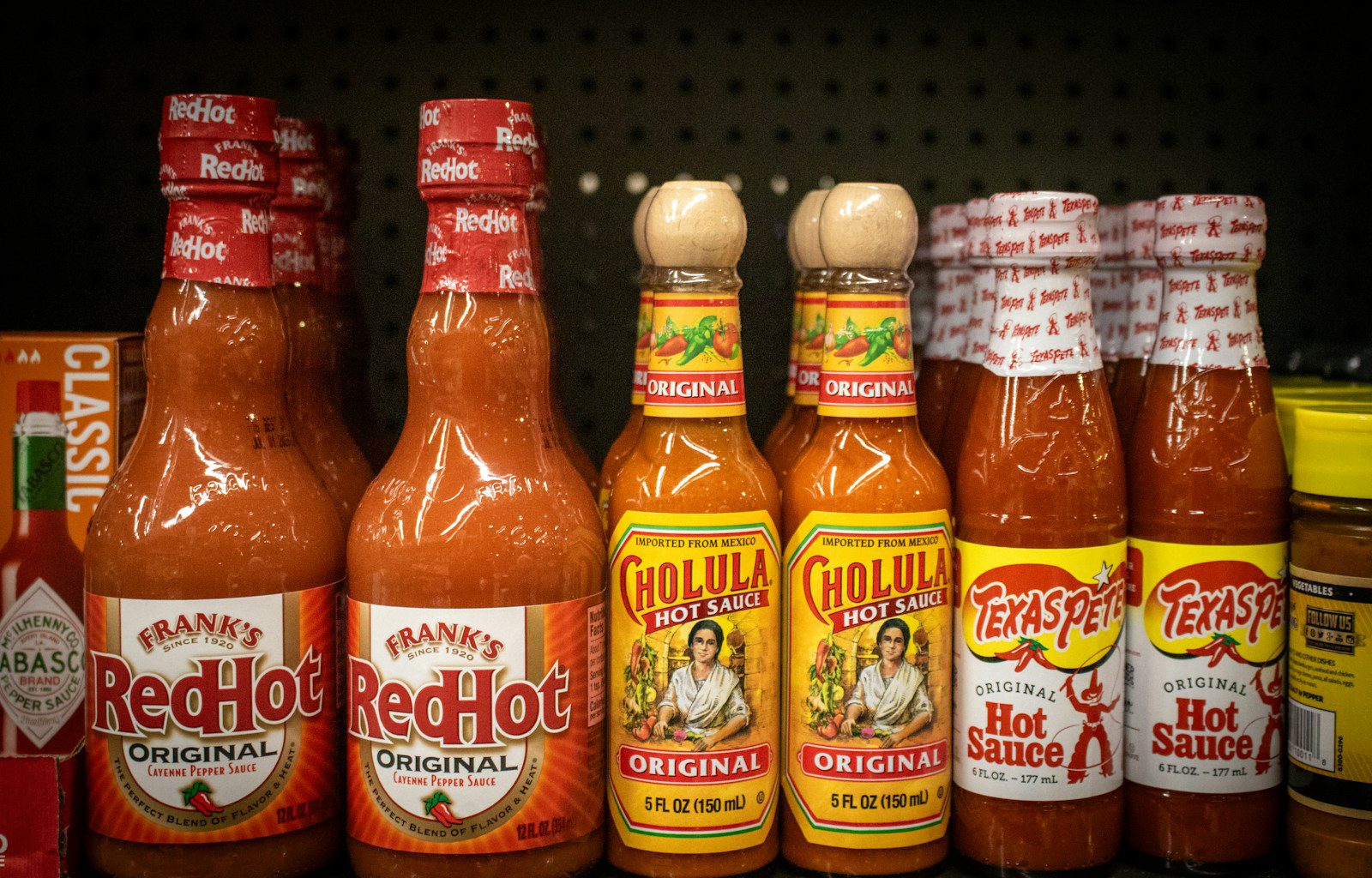 Hot sauce bottles line a store shelf.